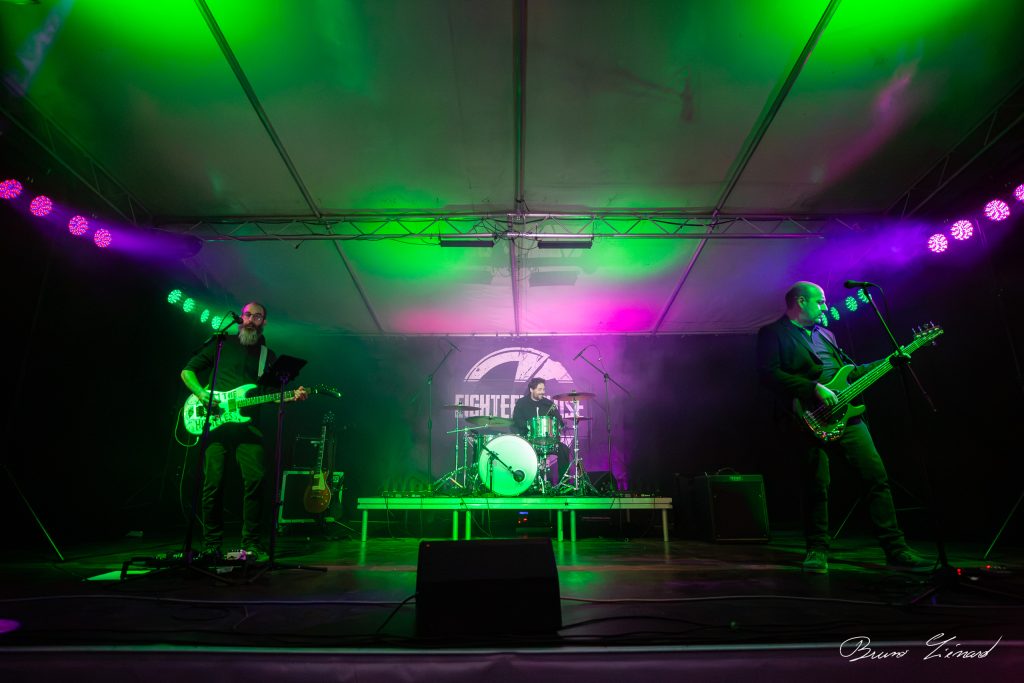 Groupe de rock sur scène avec éclairage vert et violet.